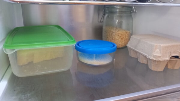 Tupperware in vetro e plastica con scaglie di Parmigiano Reggiano e Parmigiano grattugiato