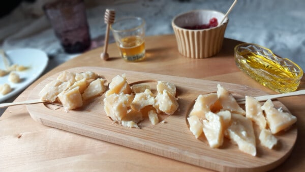 Scaglie di Parmigiano Reggiano DOP con miele e marmellate su assetta di legno durante aperitivo