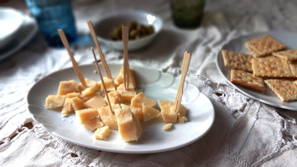 Scaglie di Parmigiano Reggiano con cracker e olive per aperitivo in un piatto bianco