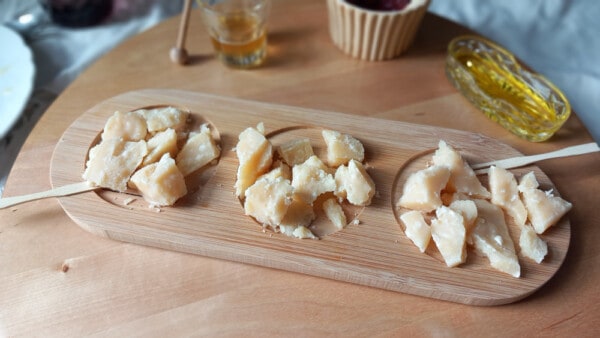 Scaglie di Parmigiano Reggiano DOP su assetta di legno durante aperitivo